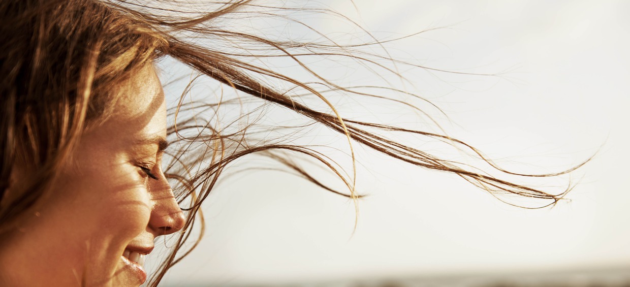 Bild på en ung kvinna i profil med vind som blåser i håret. Bild. 