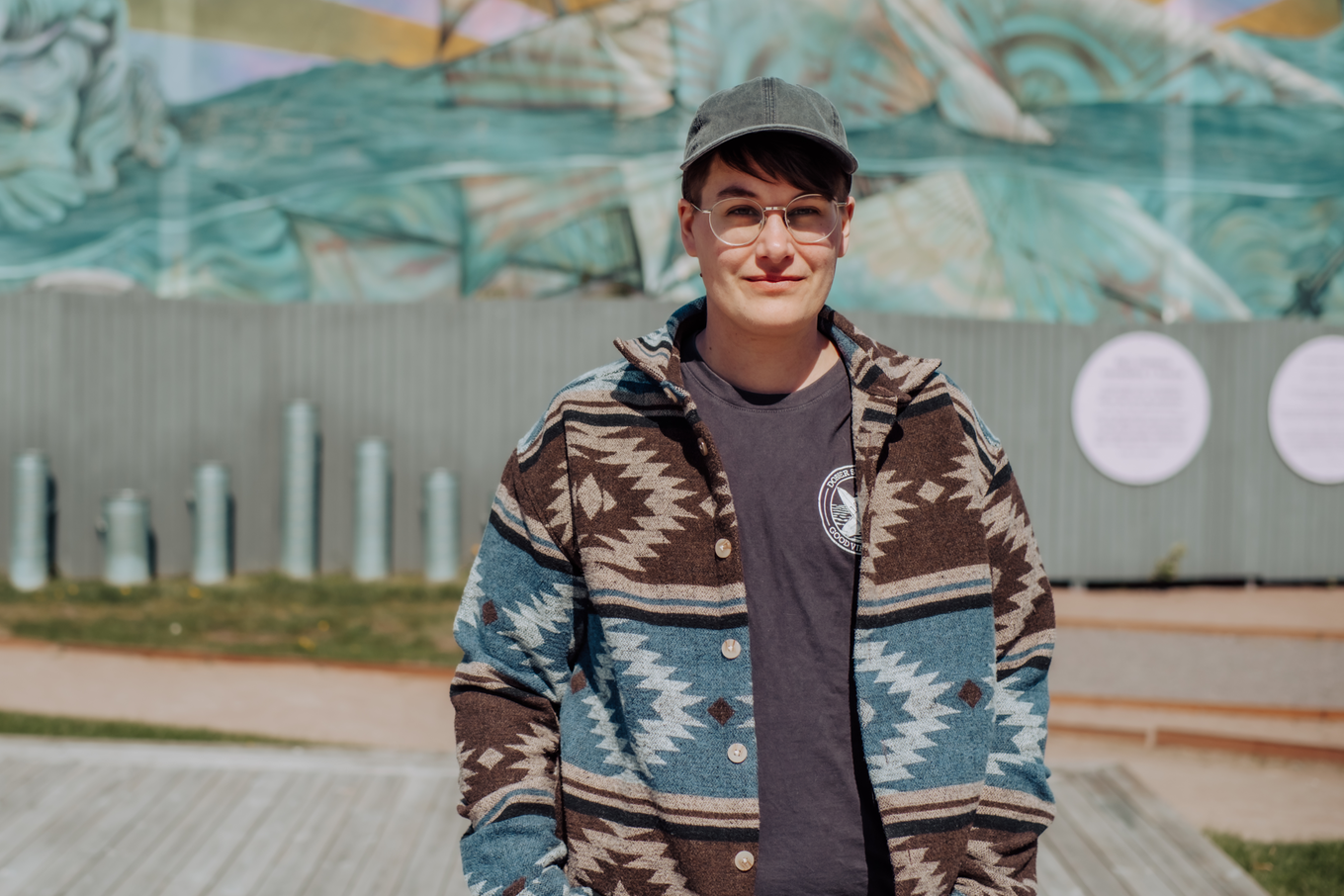 Man som står upp, tittar och ler in i kameran. Bild.