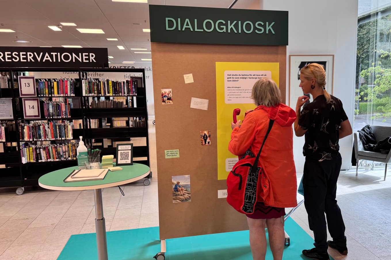 Foto på två personer med ryggarna mot kmeran som befinner sig inuti ett bibliotek. Foto