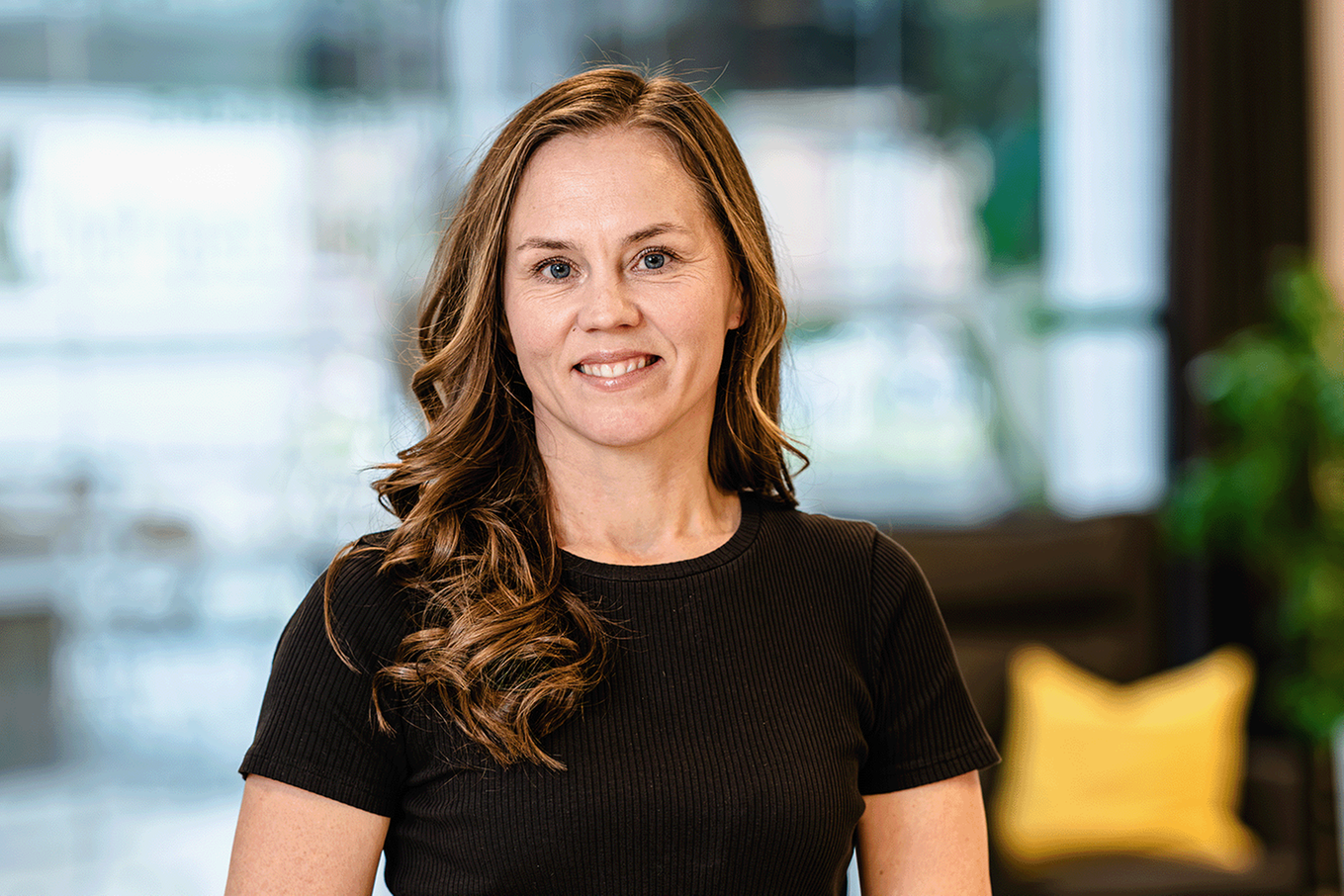 Kvinna med långt hår ler mot kameran. Bild. 